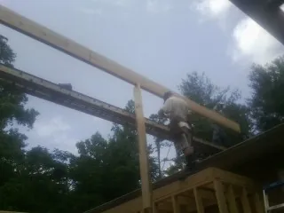 Carpenter setting a ridge beam over a new addition frame — Ice Dam Removal by Roofing Brothers in East Amherst