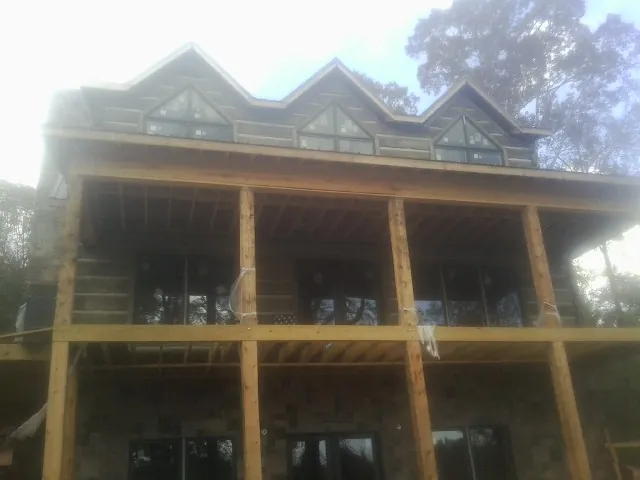 Dormers and porch framing on a large log home under construction — Roof Coating work by our crew in East Amherst