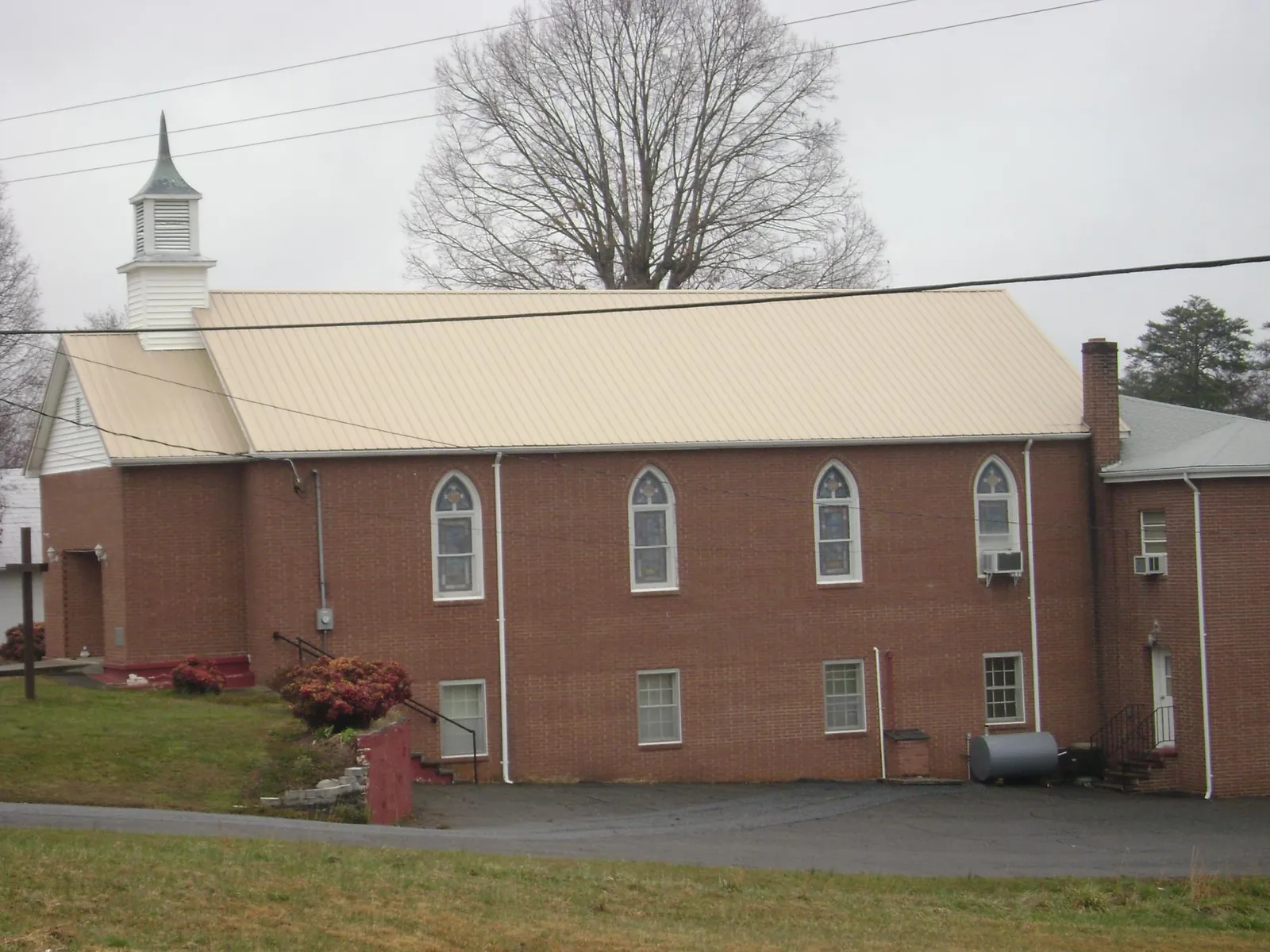 New tan metal roof on a brick church with a white steeple in East Amherst