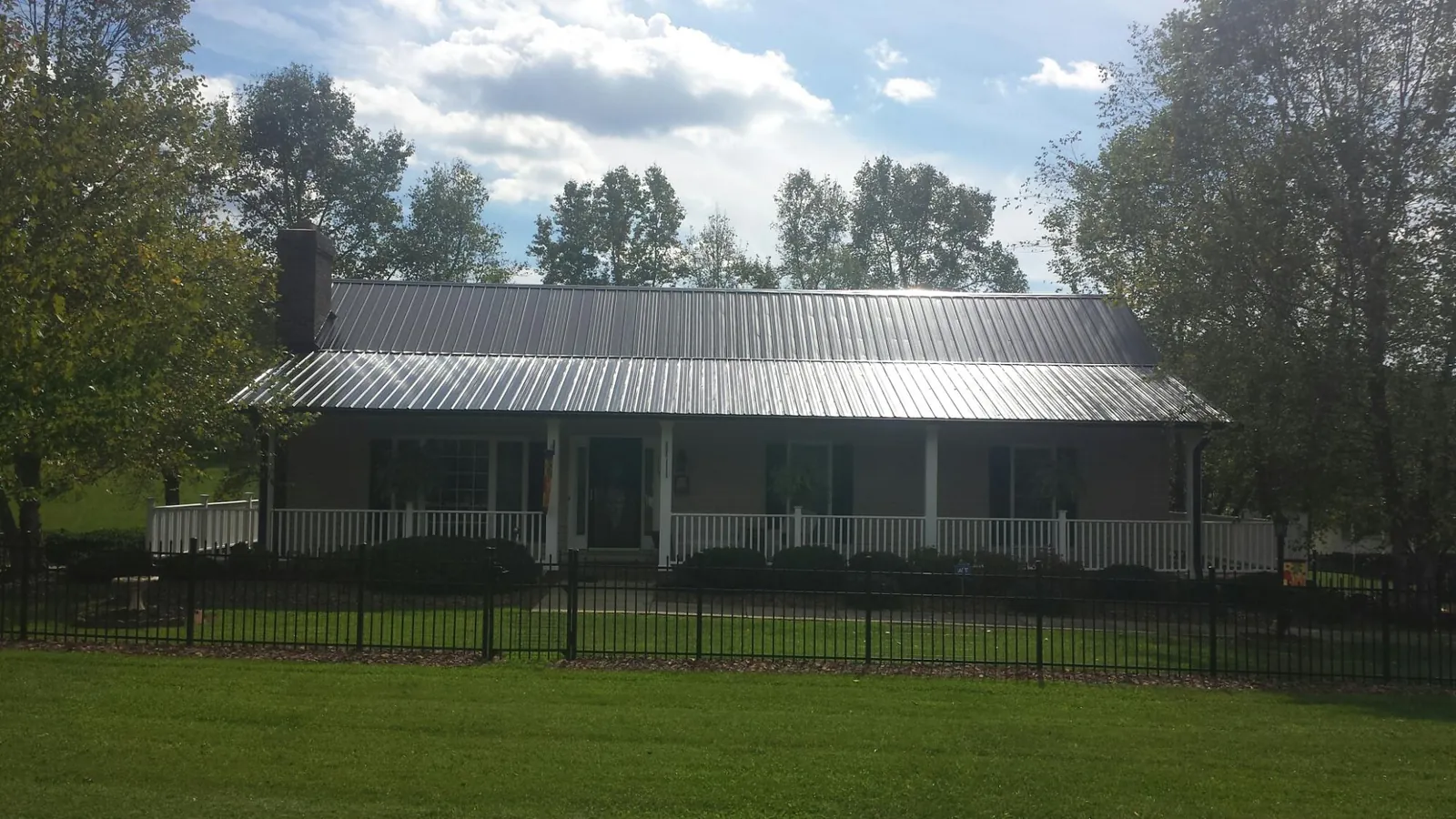 Gray metal roof on a brick ranch with a full width front porch — Gutter Guard Installation work by our crew in East Amherst