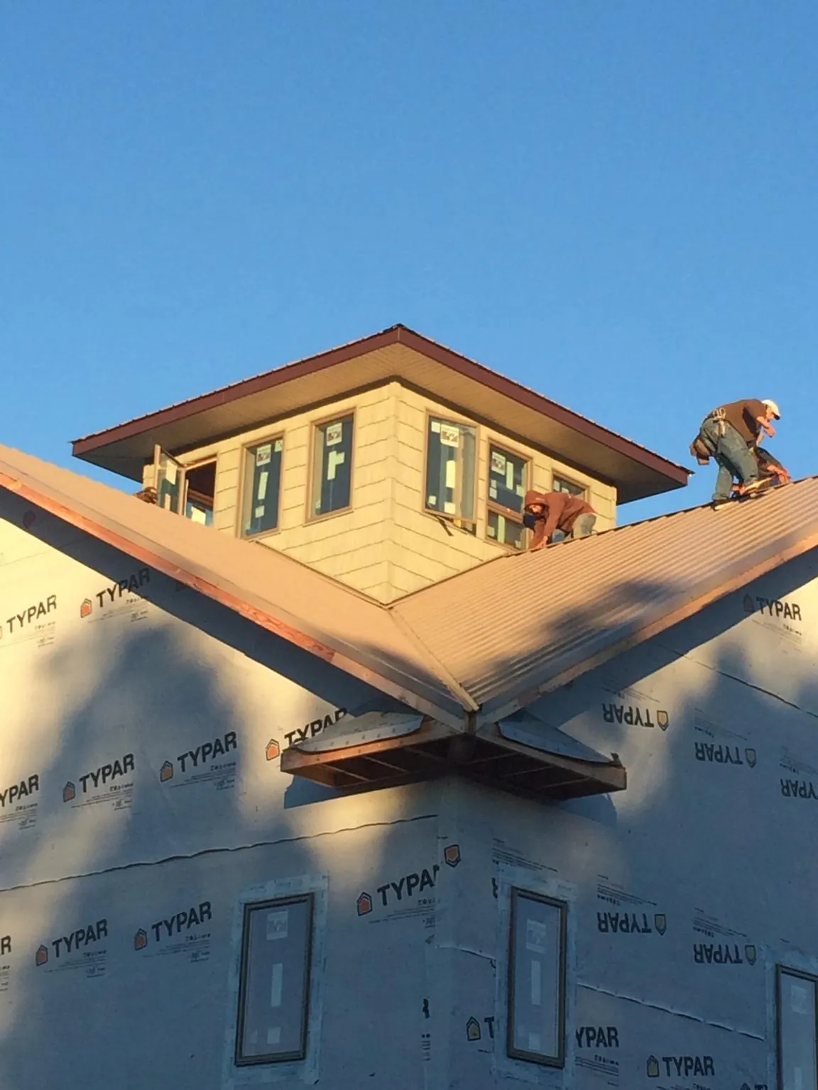 Roofers working around a rooftop cupola on a new metal roof at sunset — Roof Waterproofing in East Amherst by Roofing Brothers